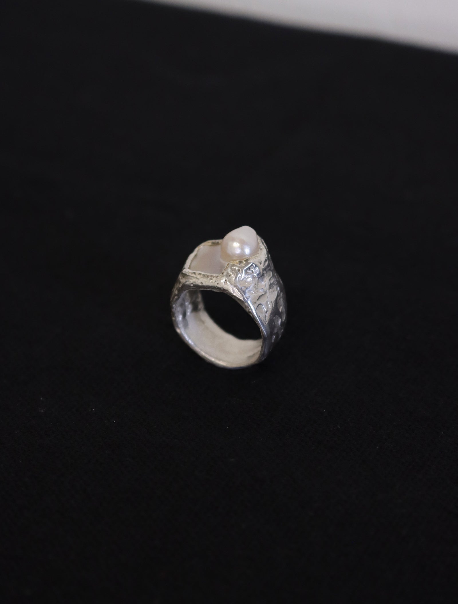Silver ring with a pearl and diamond on a black background